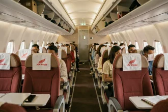 Intérieur de la cabine économique d'un avion Air India avec passagers assis dans des sièges rouge et beige