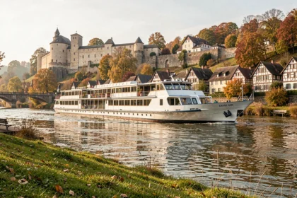 Croisière sur le Rhin avec un bateau de croisière fluviale passant devant un village médiéval allemand et un château sur les hauteurs